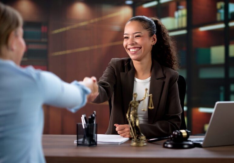 Female Lawyer And Hispanic Client Seal Judicial Agreement With Handshake